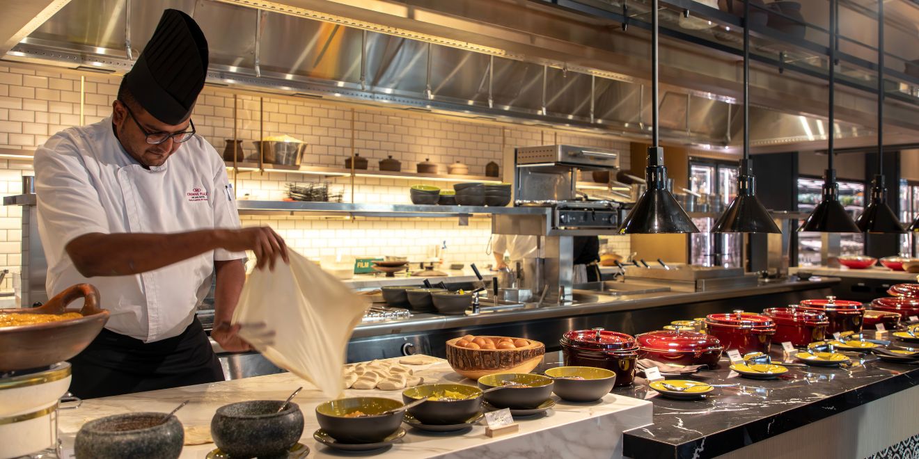 hotel chef in live-cooking station at the buffet table