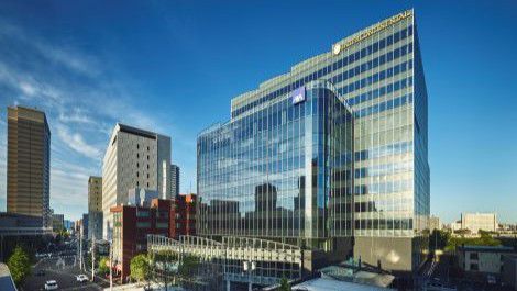 Modern glass office building reflecting the blue sky in an urban district