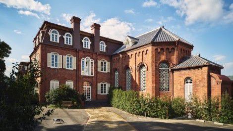 Historic red‑brick building with arched windows and a pitched roof under a clear sky