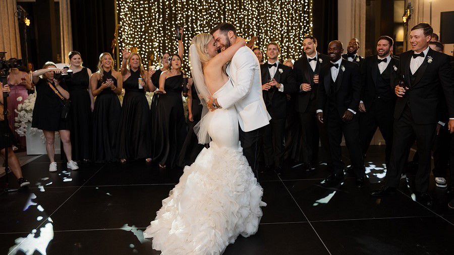 Bride and groom embracing in front of wedding party