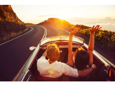 Couple driving in drop top convertible during sunset