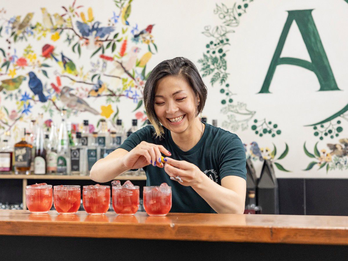 Woman preparing red cocktails at a distillery bar.