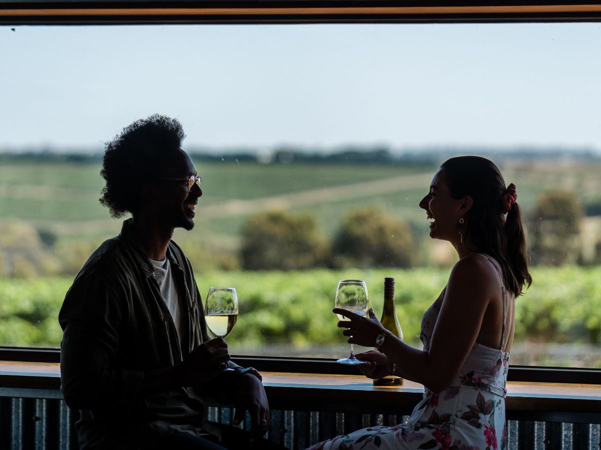 Two people enjoying wine with vineyard views.