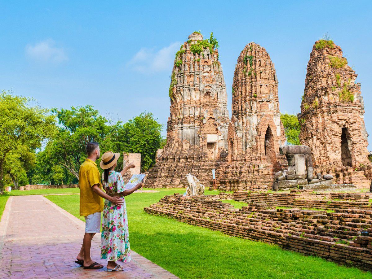 Visitors exploring historic temple ruins in a scenic outdoor setting.