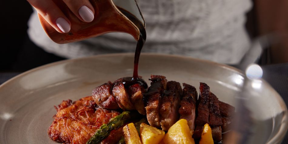 Sauce poured over sliced steak with vegetables and potatoes