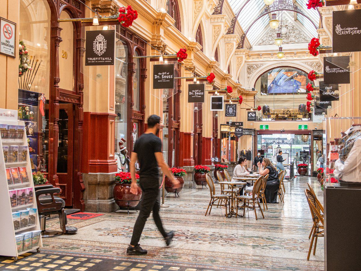 Indoor historic arcade with shops, cafés, and pedestrians.