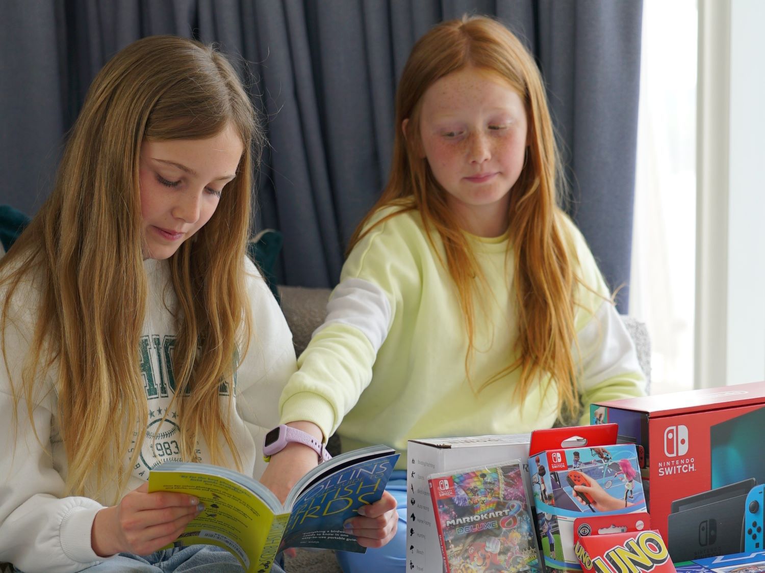 Two girls in hotel room with varuous game options such as Nintendo and Uno