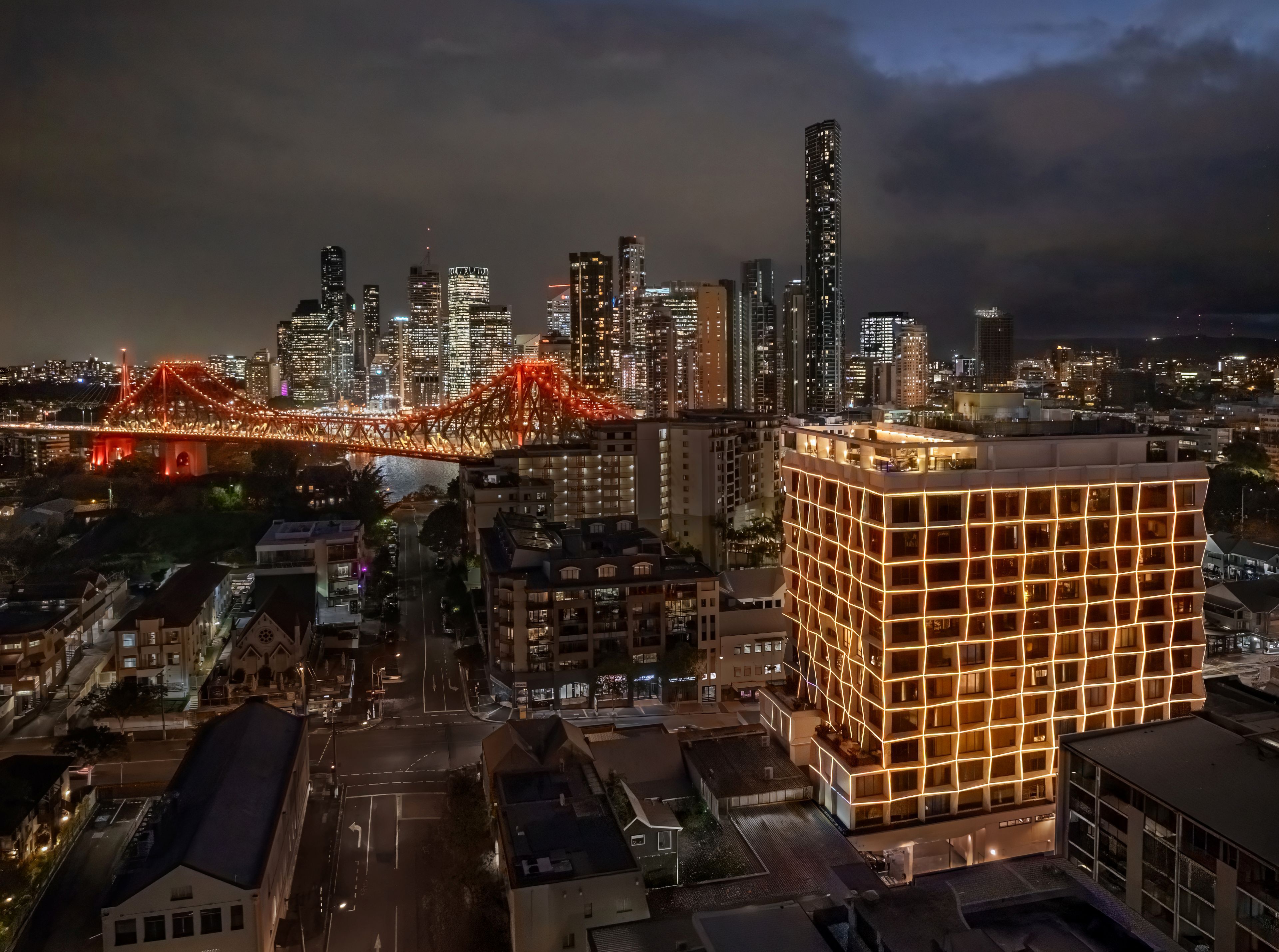 Nighttime city skyline with illuminated bridge and buildings