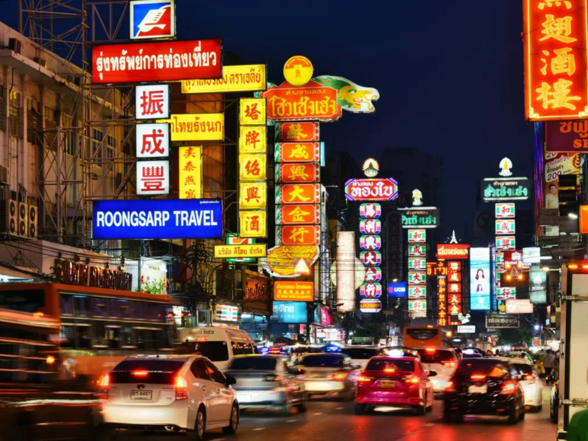 Vibrant city street illuminated by colorful neon signs at night.