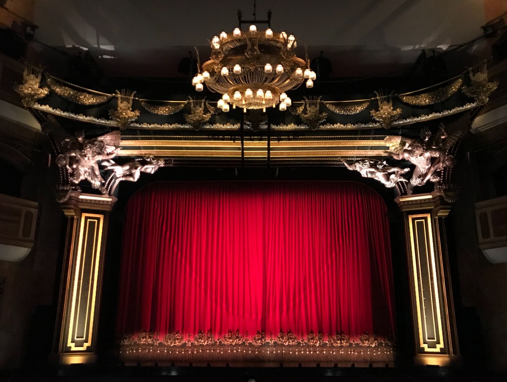 dramatic stage with closed red velvet curtain in large theater