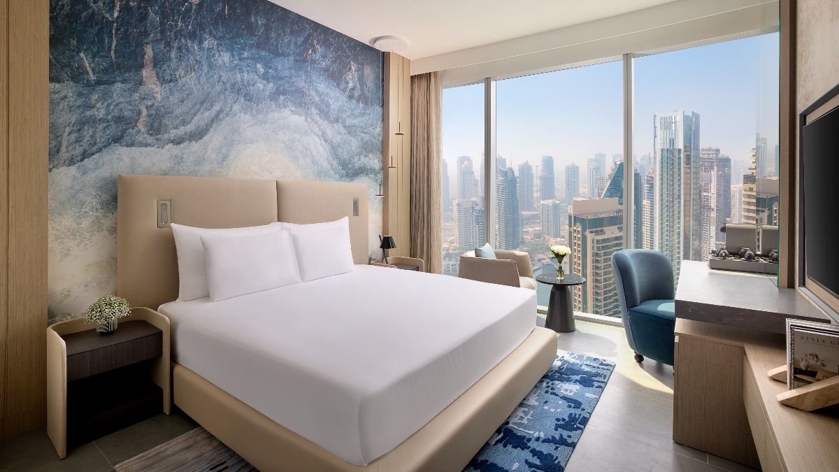 Modern hotel bedroom with city skyline view through windows