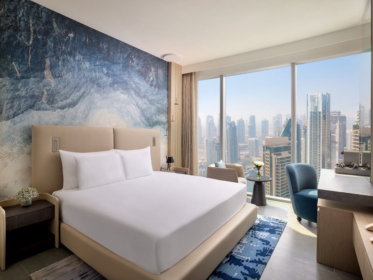 Modern hotel bedroom with city skyline view through windows