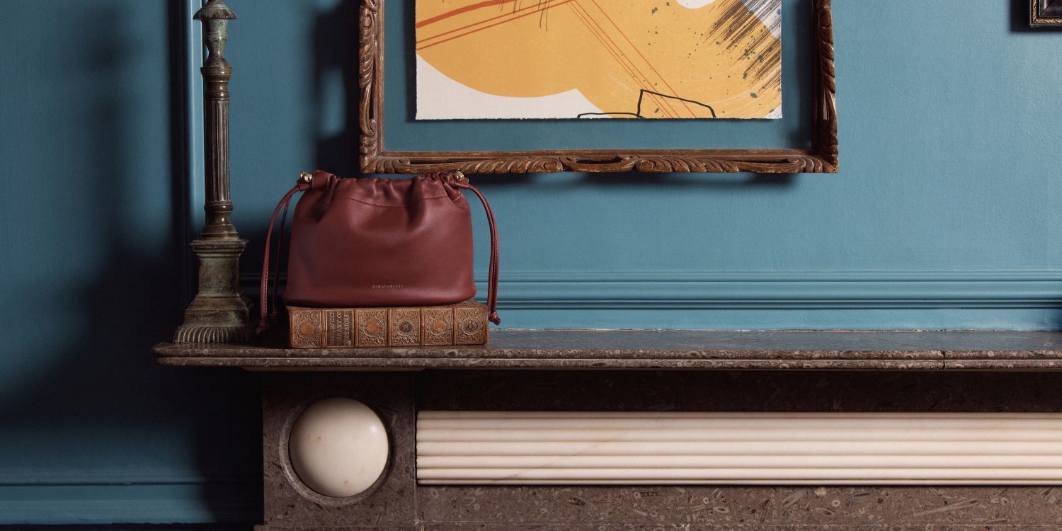 Cherry red Strathberry handbag placed on a fireplace