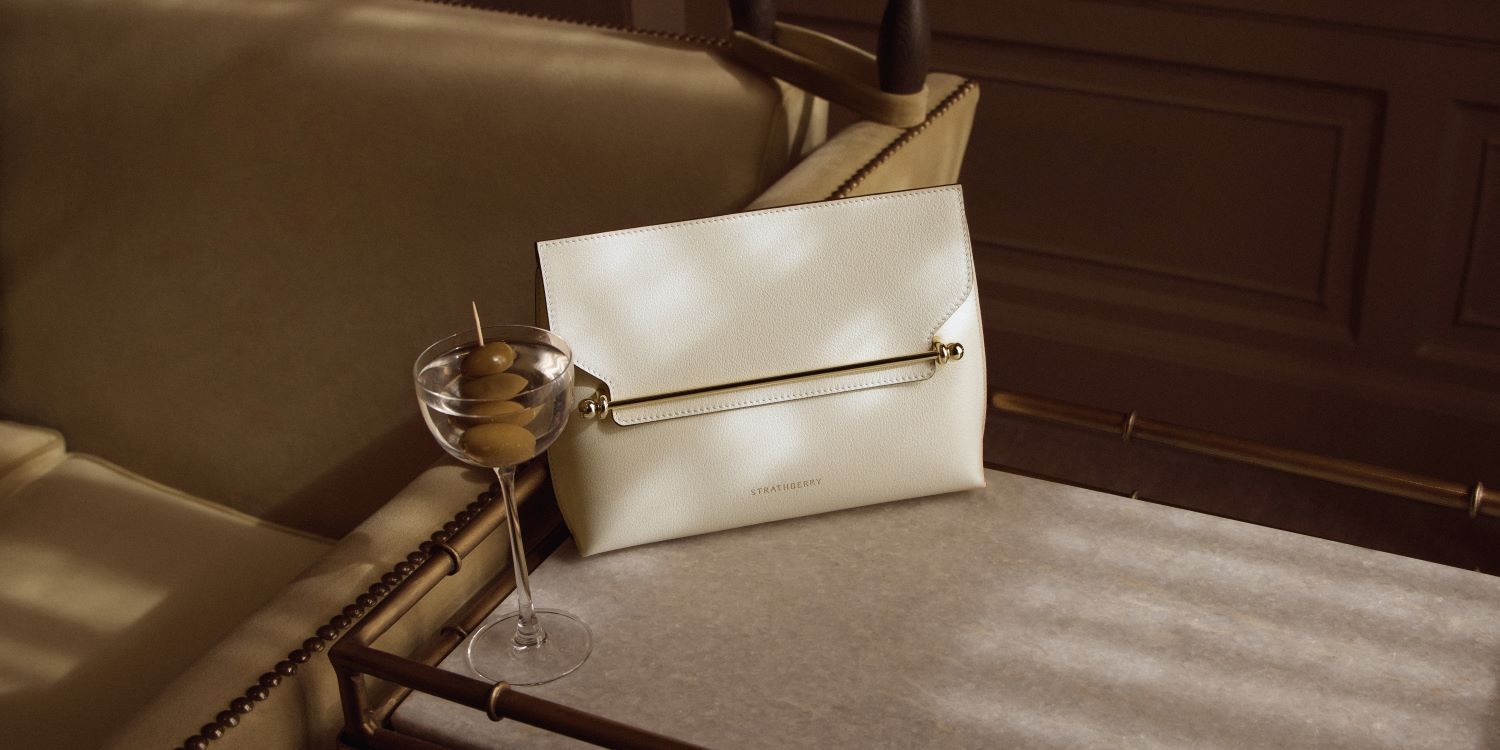 Neutral Strathberry handbag placed next to a martini cocktail