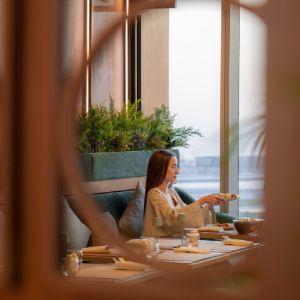 Woman dining by a window overlooking the waterfront