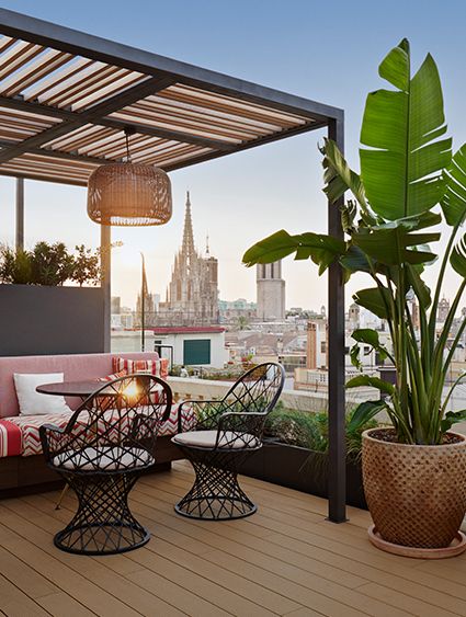 rooftop bar with inviting lounge seating, lush plants, overlooking barcelona