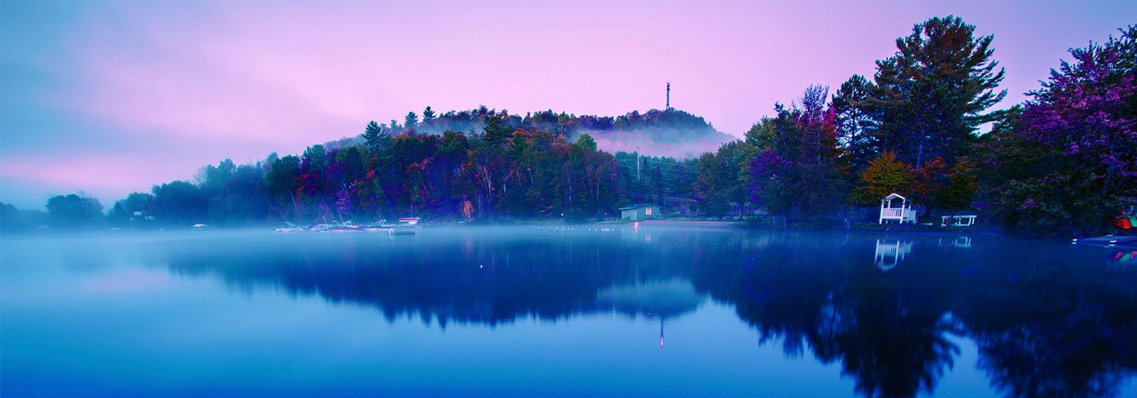 View of shoreline with early morning mist on across the water and in the tree of the surrounding hills