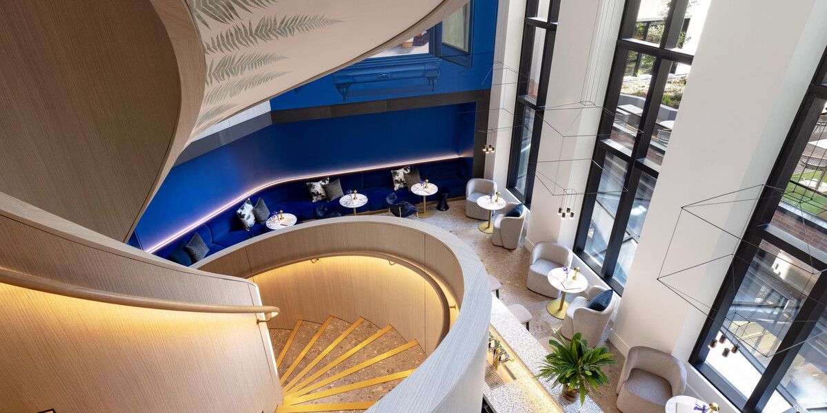 Spiral staircase overlooking elegant blue seating area.