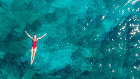 Swimmer floating in blue ocean