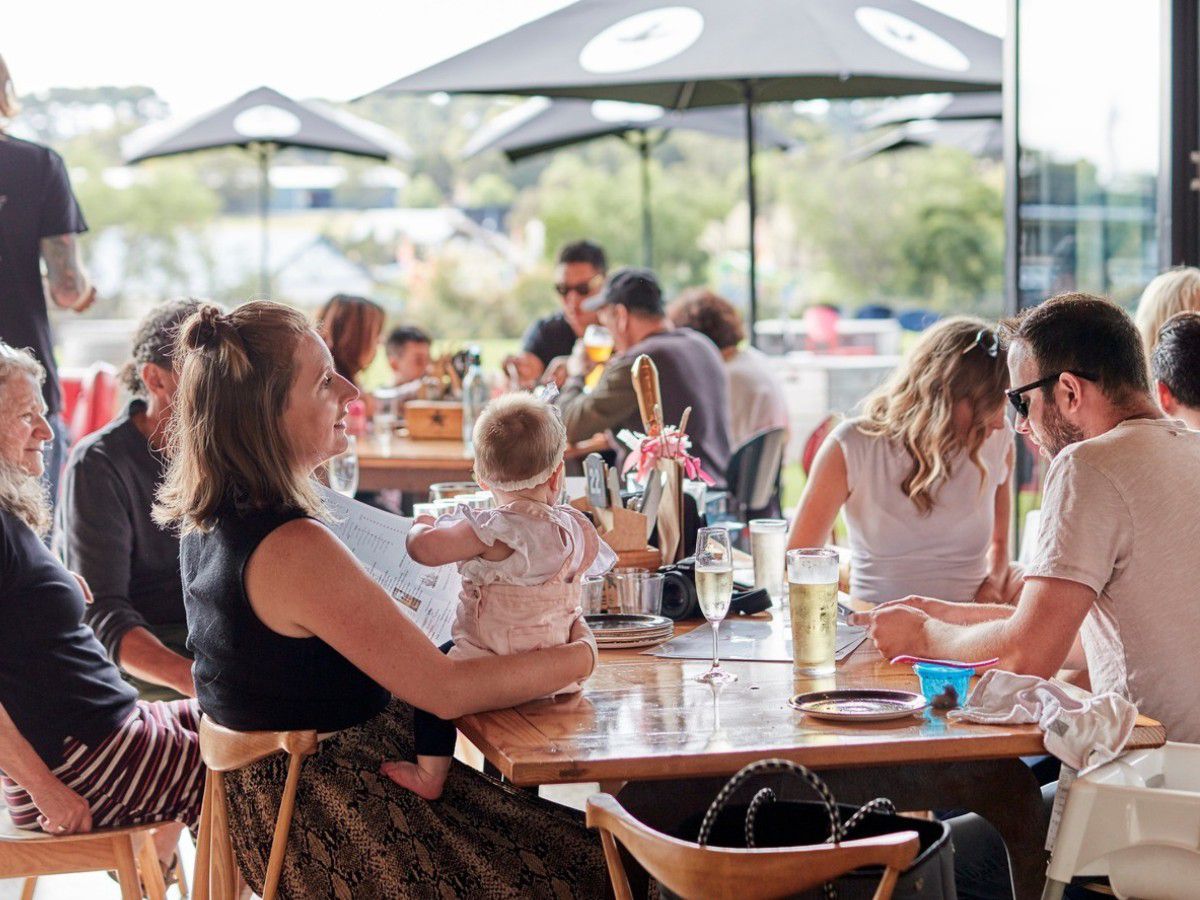 Family dining outdoors at a busy cider venue.