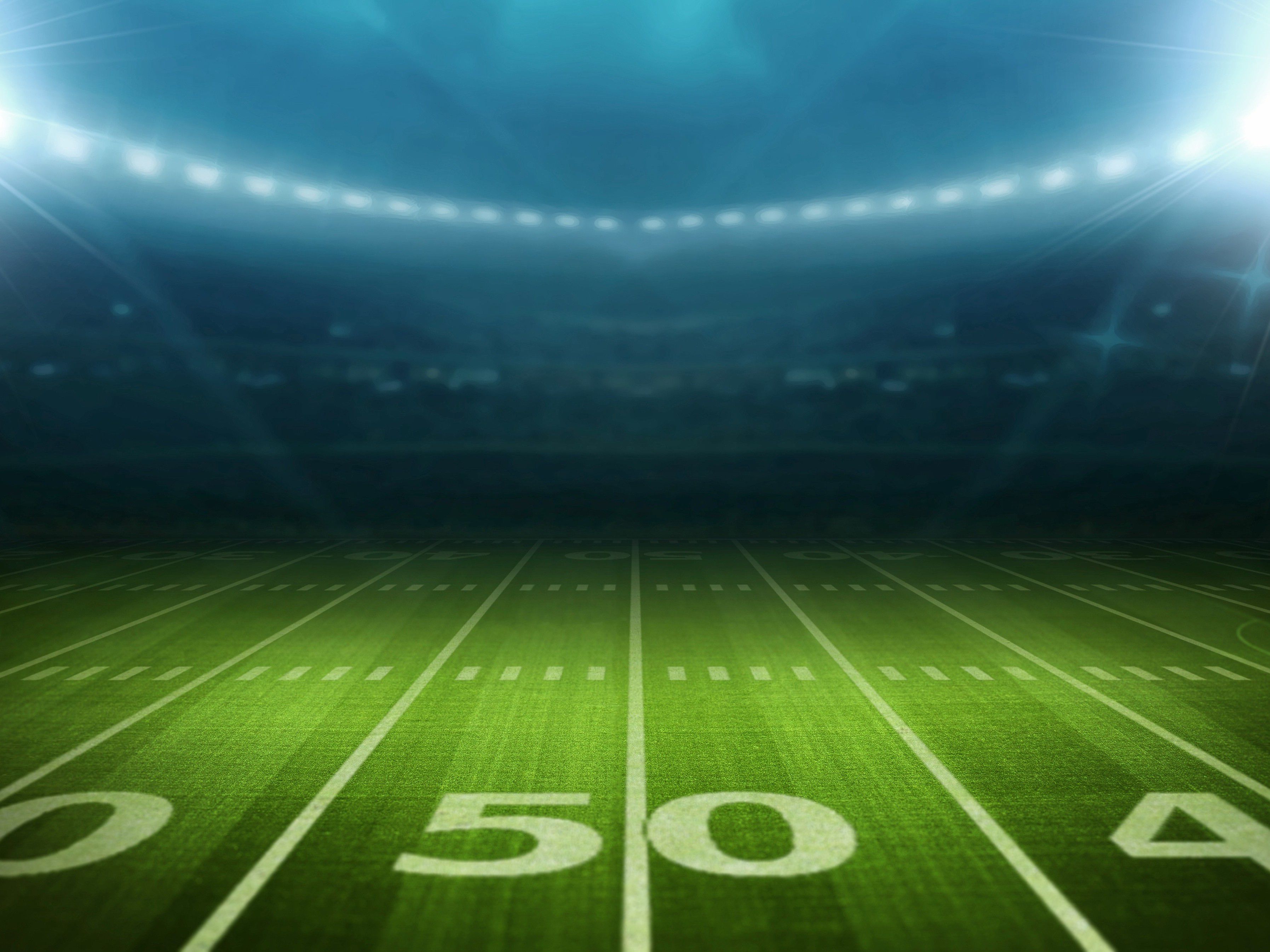 American football field illuminated by stadium lights at night