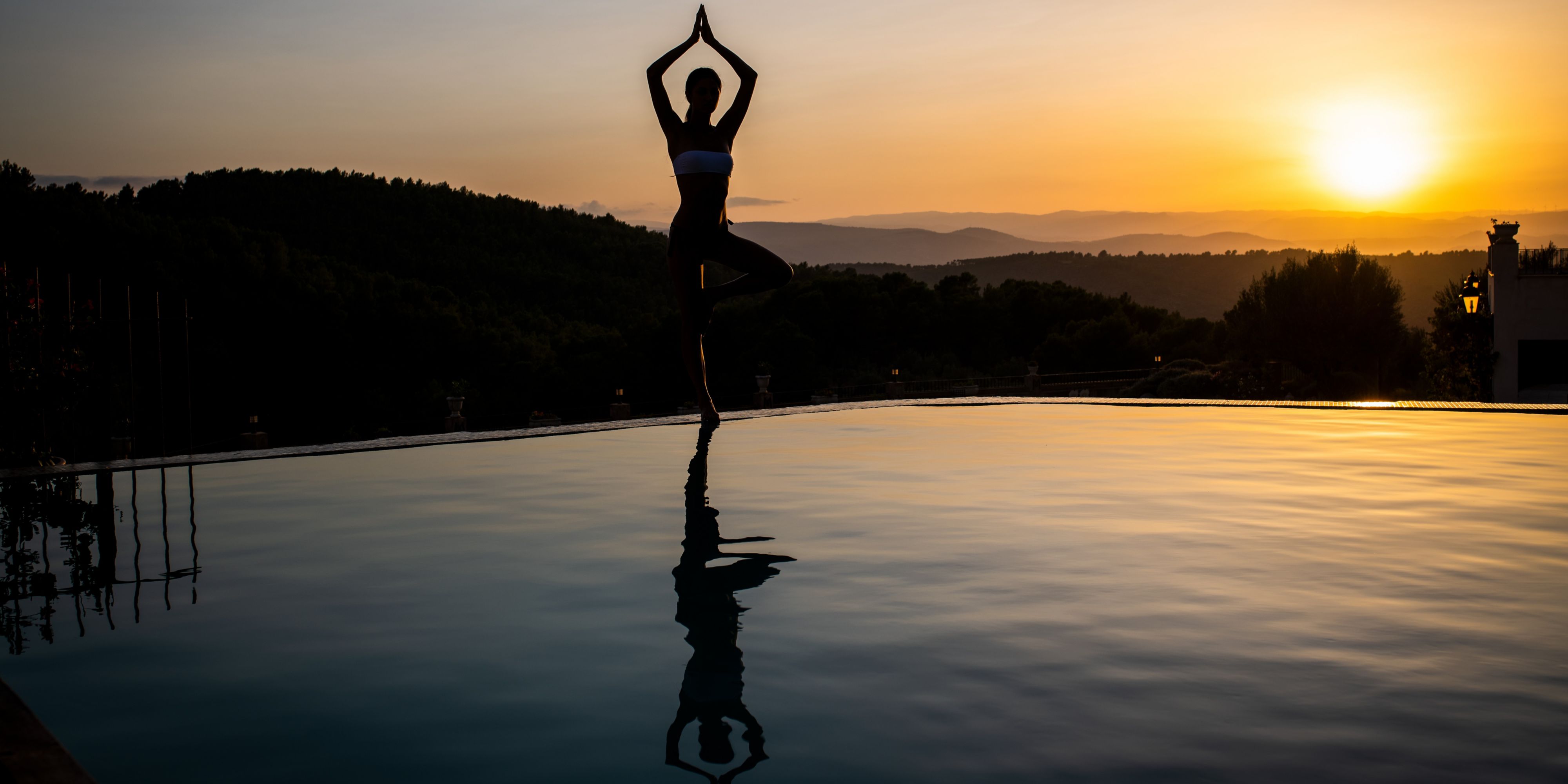 Yoga al atardecer junto a la piscina desbordante