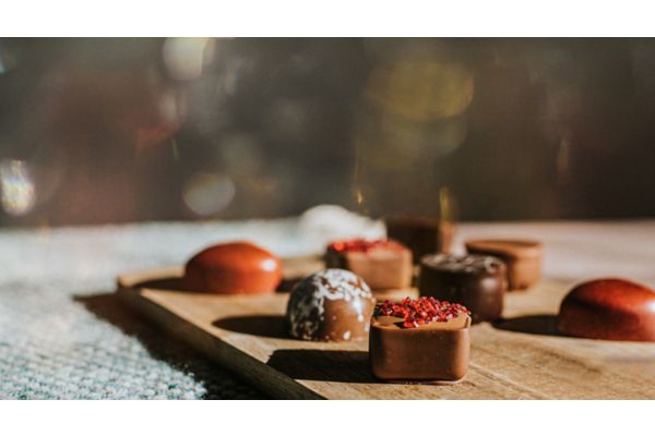 Close up of various flavoured / shaped / coloured luxury chocolates on a wooden surface with space for copy.