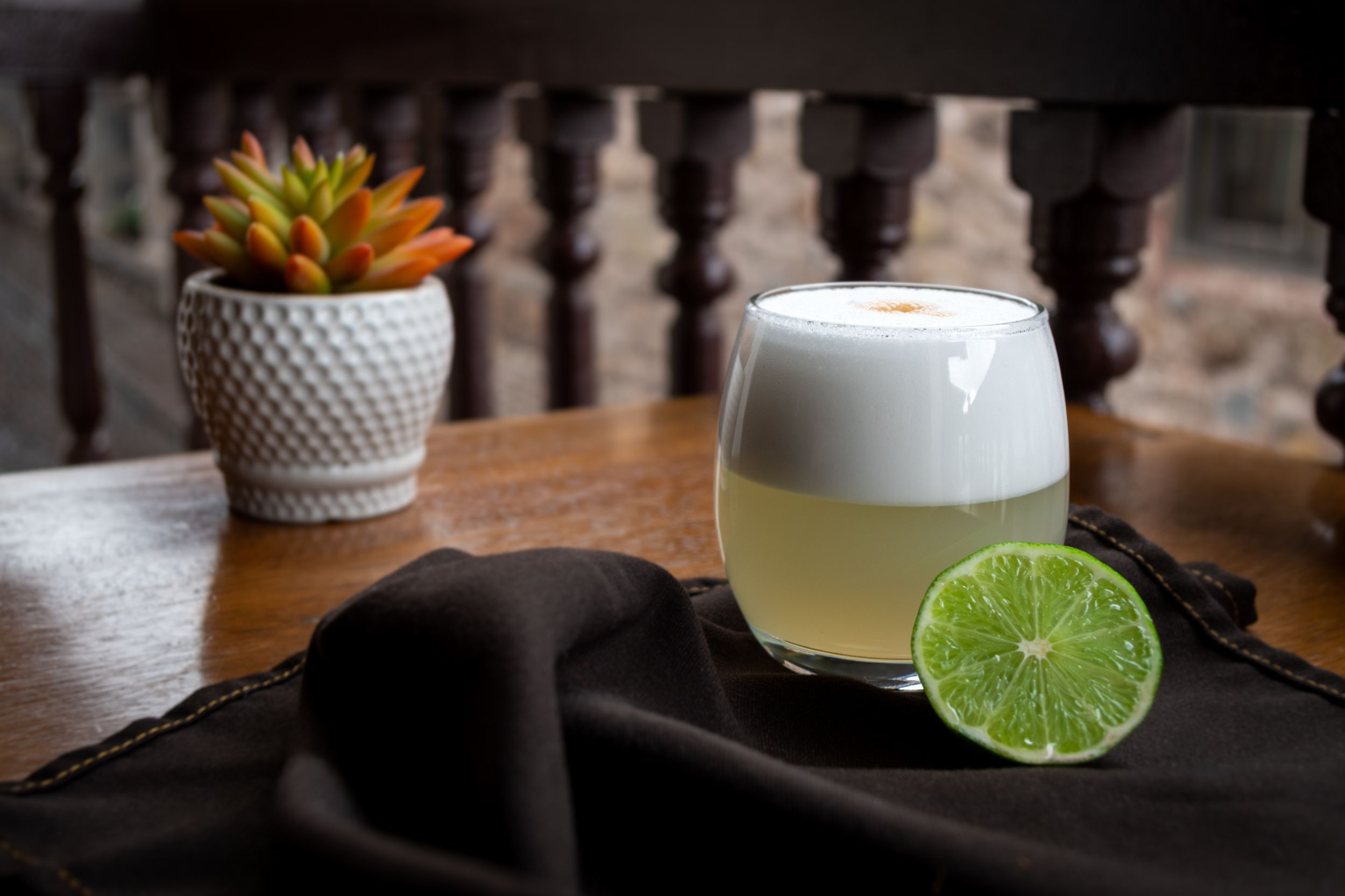 Classic Peruvian Pisco Sour served on a table with a lime on an unfocused background