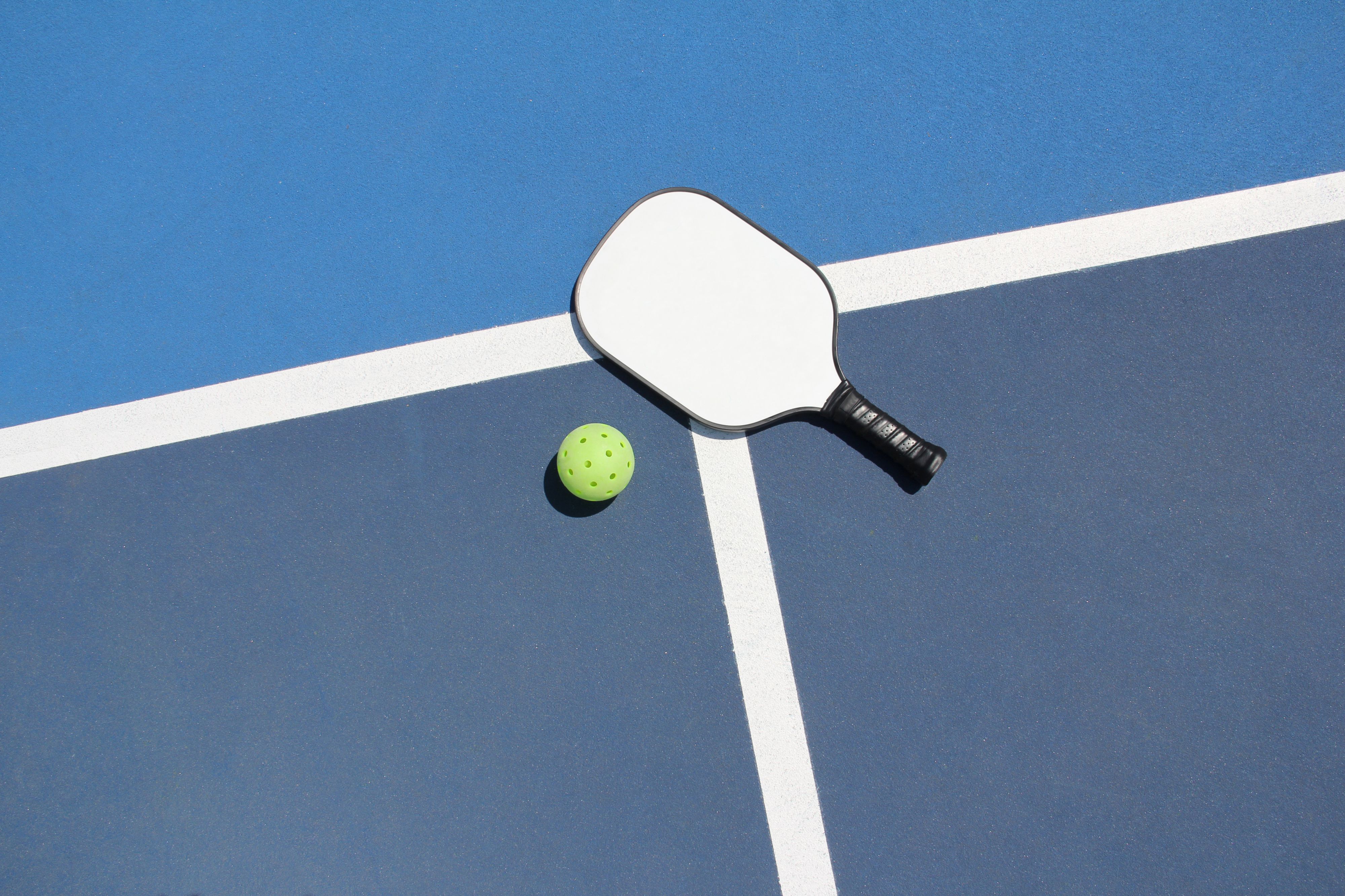  High angle view of pickleball court with paddle and ball outdoors