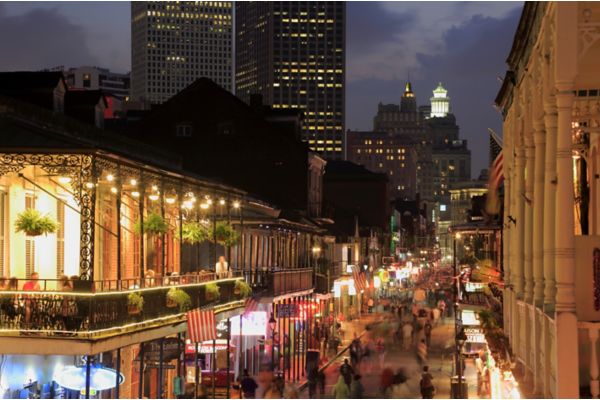 Night view of Bourbon street with downtown buildings in the background.