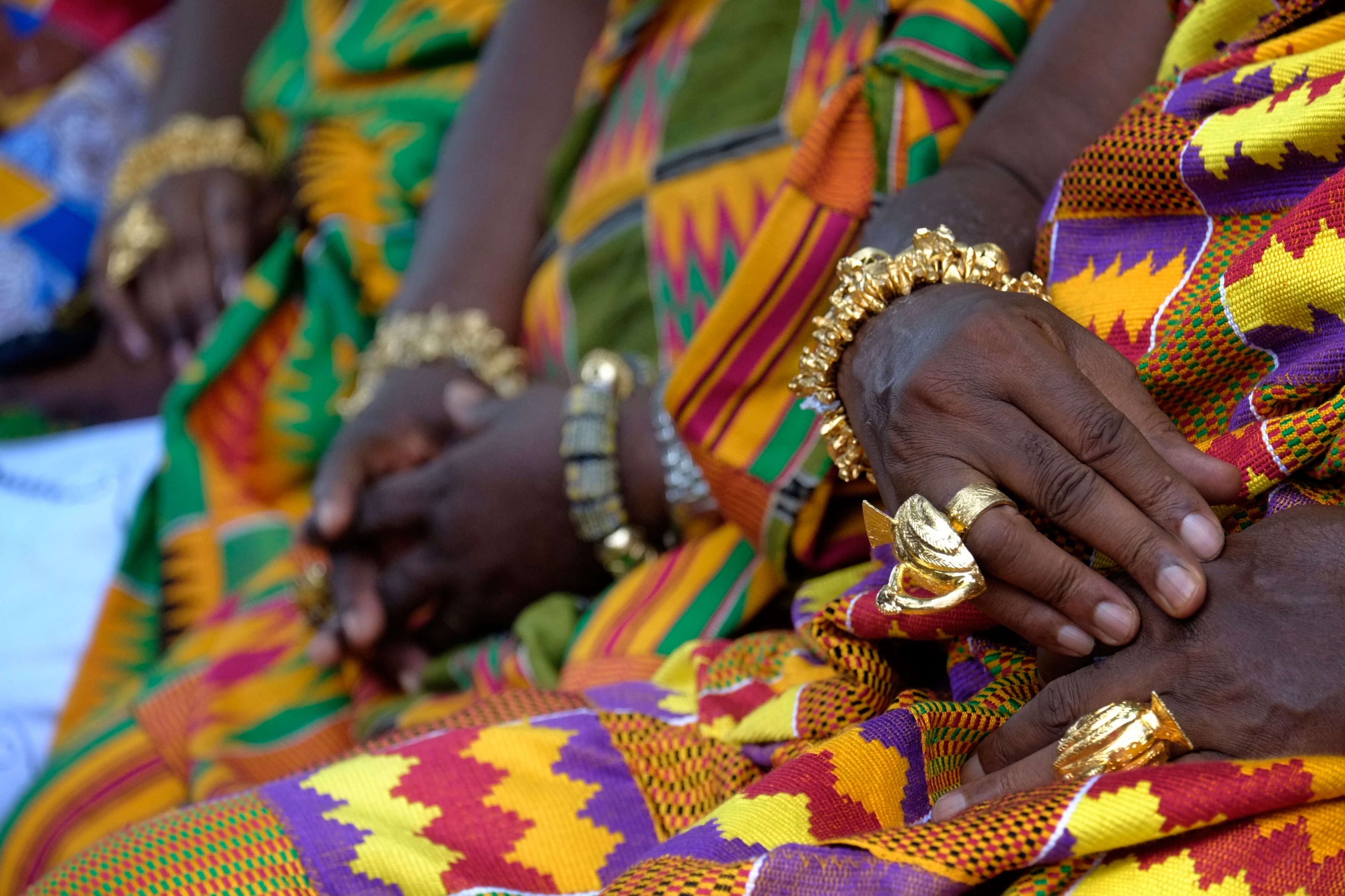 Close-up of hands wearing gold jewelry and colorful patterned fabric