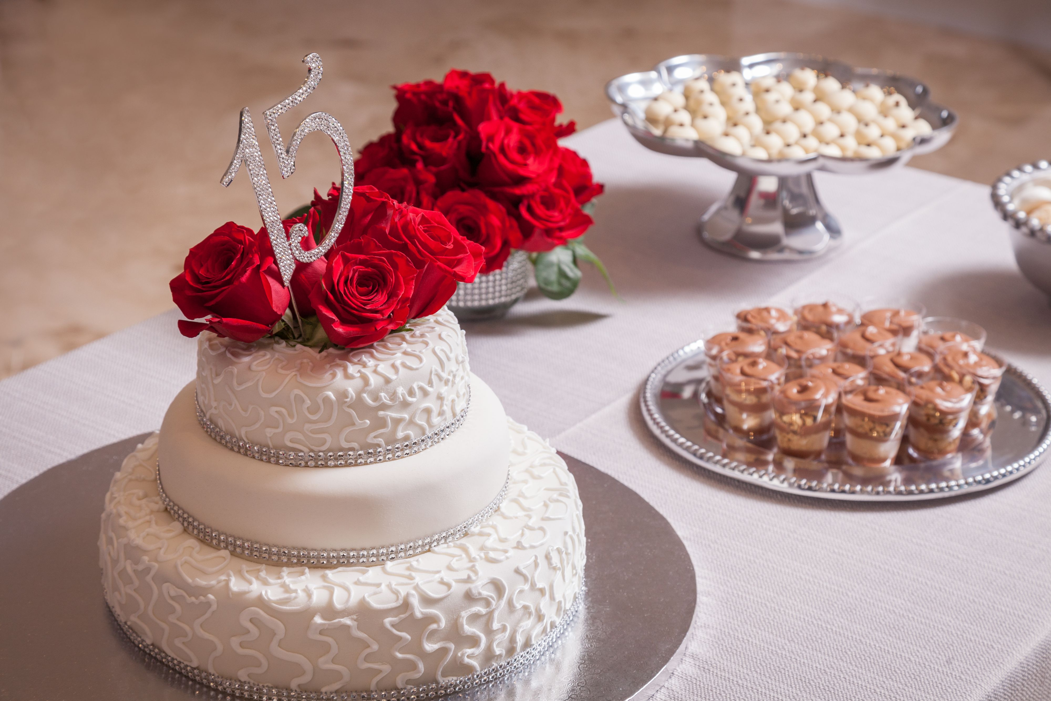 Quinceanera cake on table with other desserts.