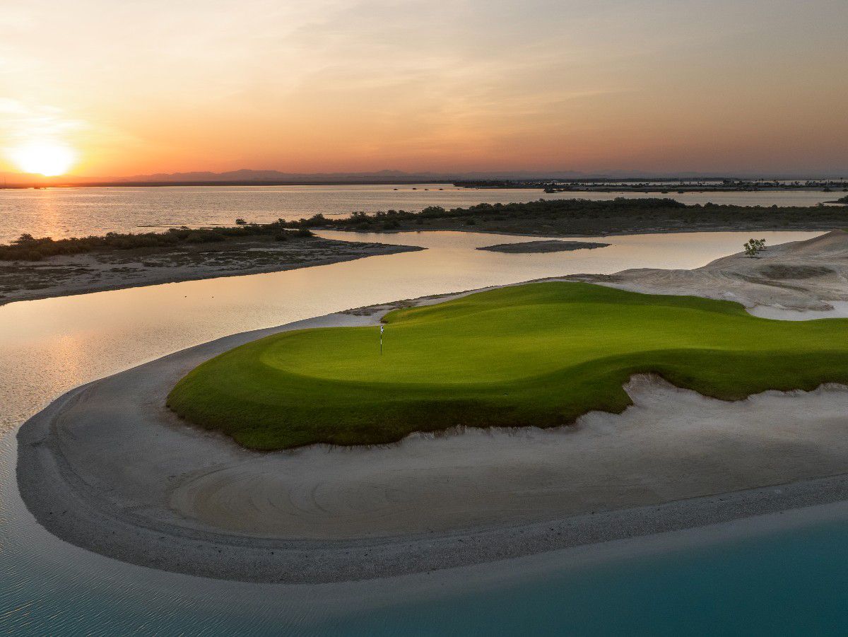 Sunset over coastal golf course surrounded by water