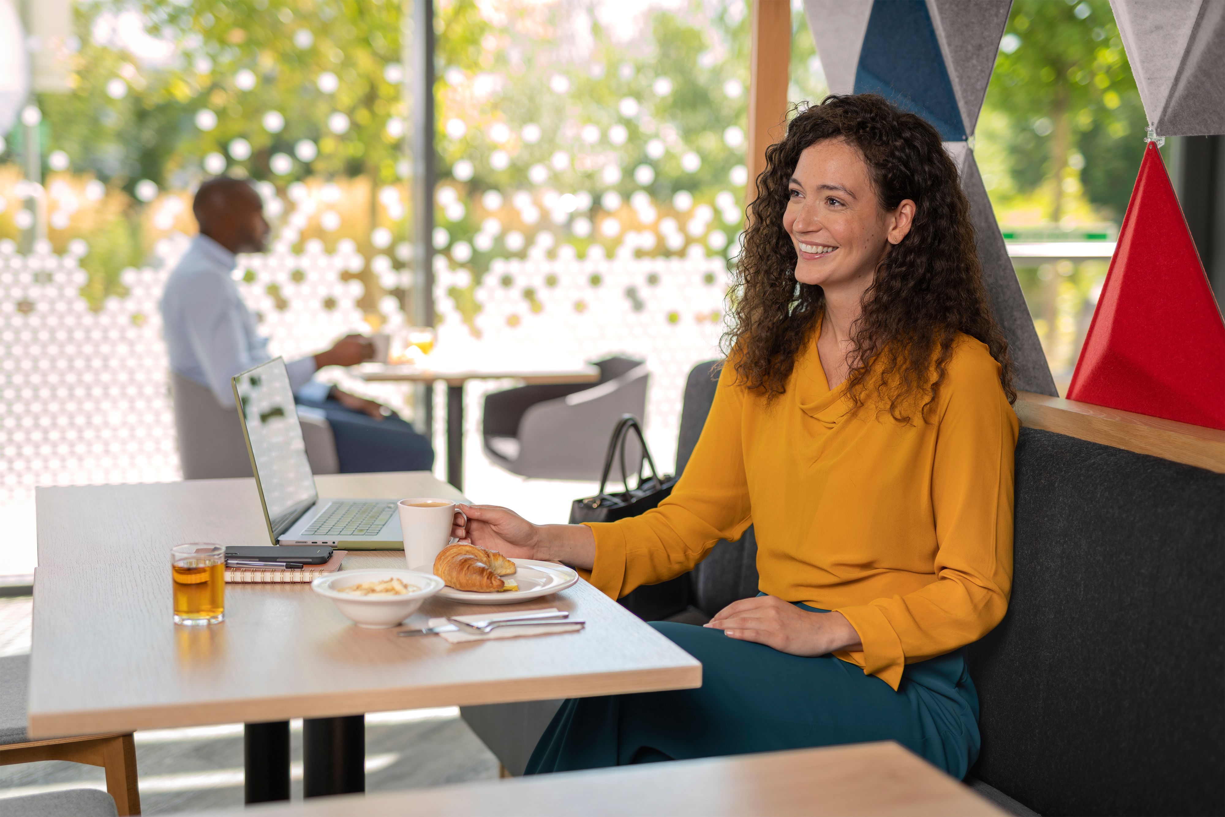 Eine Geschäftsfrau sitzt mit ihrem Laptop beim Frühstück