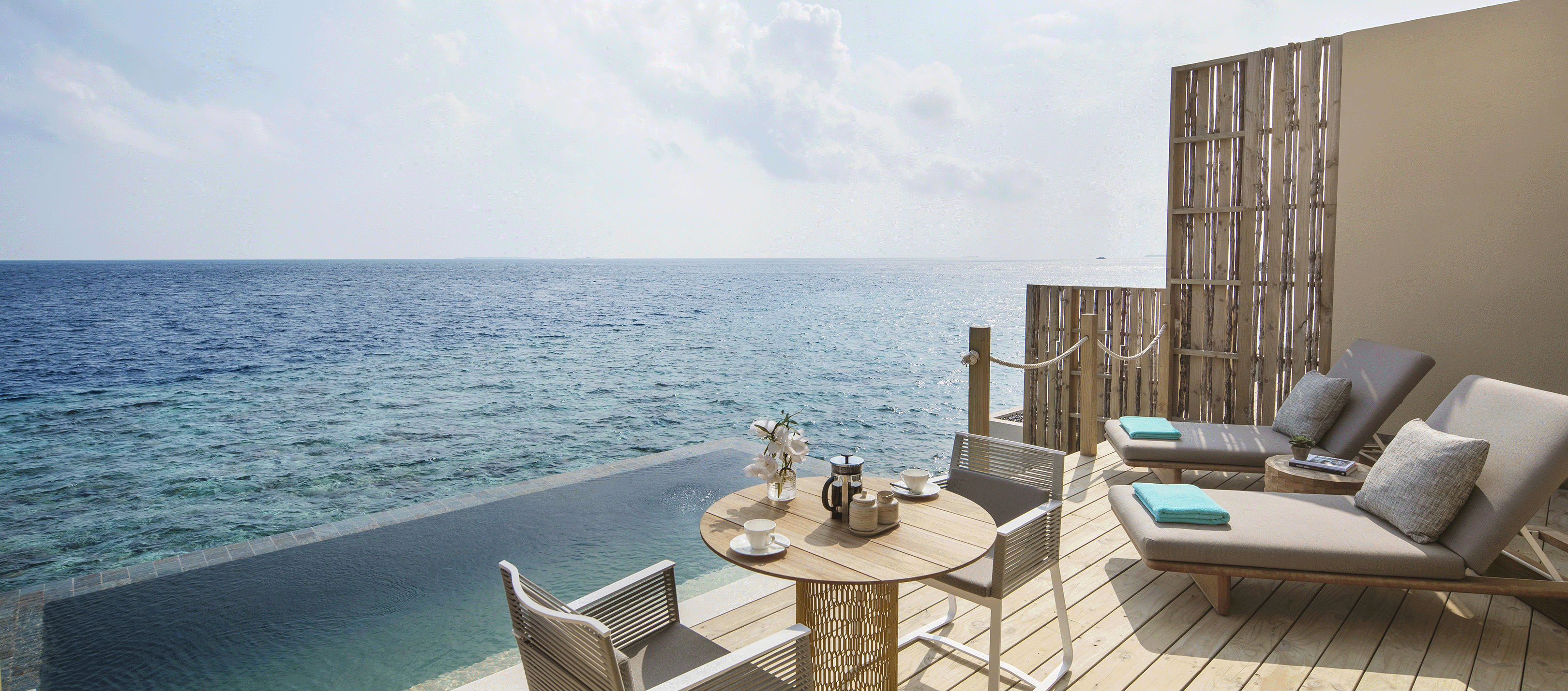 Kleiner Tisch mit Stühlen auf der Terrasse direkt neben dem Meer 
