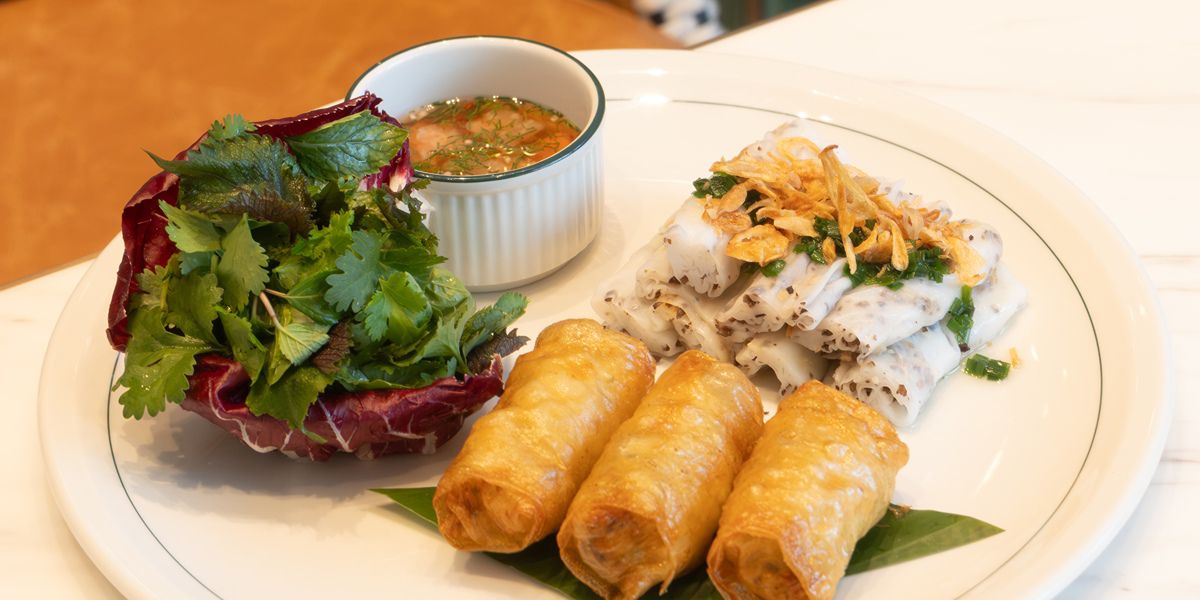 Vietnamese-style squid cakes, rice rolls, spring rolls, and herbs on plate