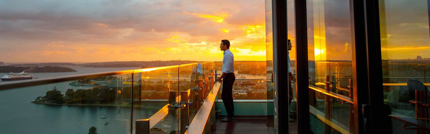 Man looking outward on from a glass walled balcony