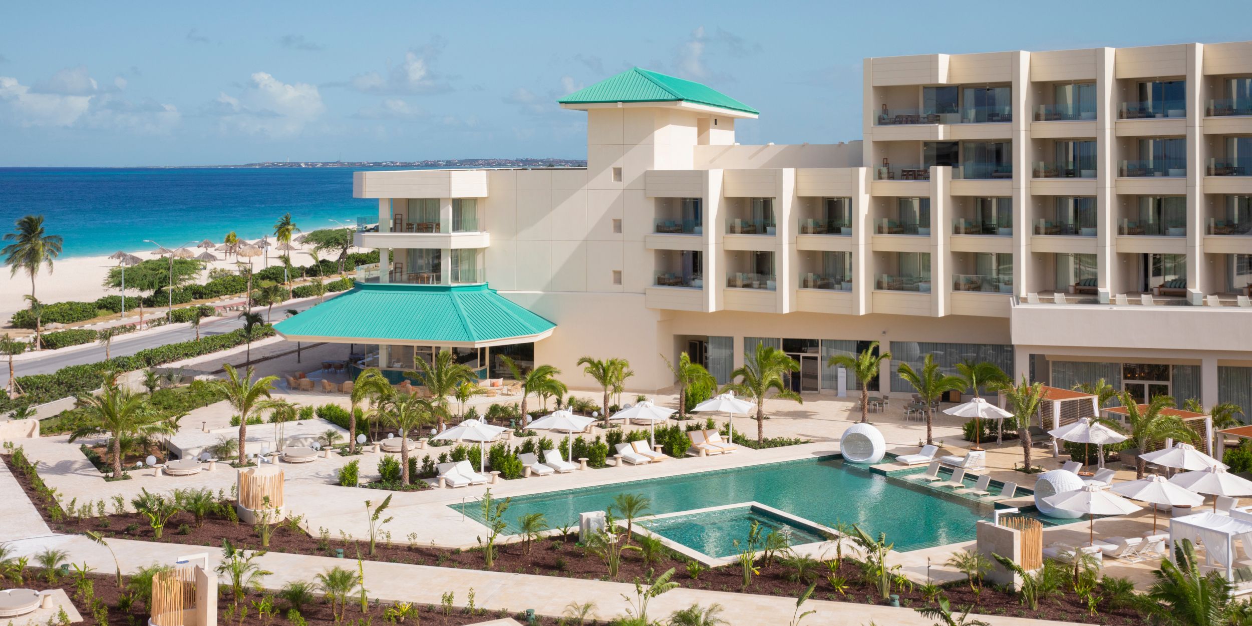 Beachfront resort with pool, palm trees, and ocean views