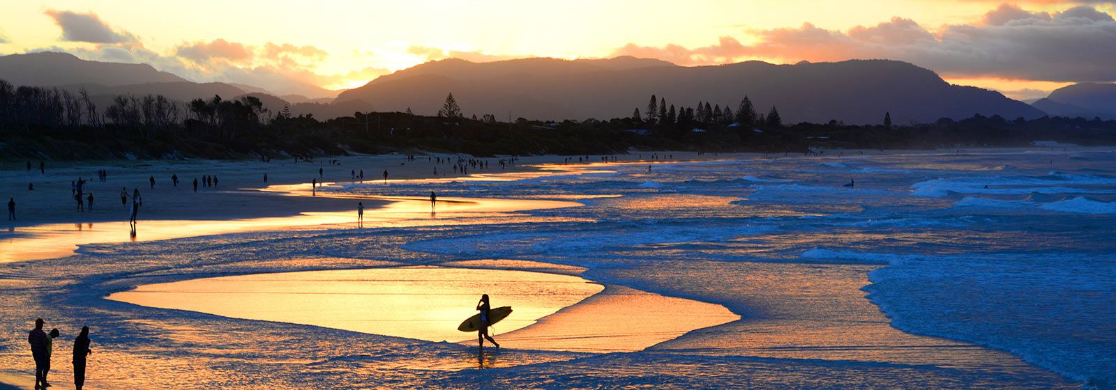 Surfer, die in der Abenddämmerung am Strand spazieren 