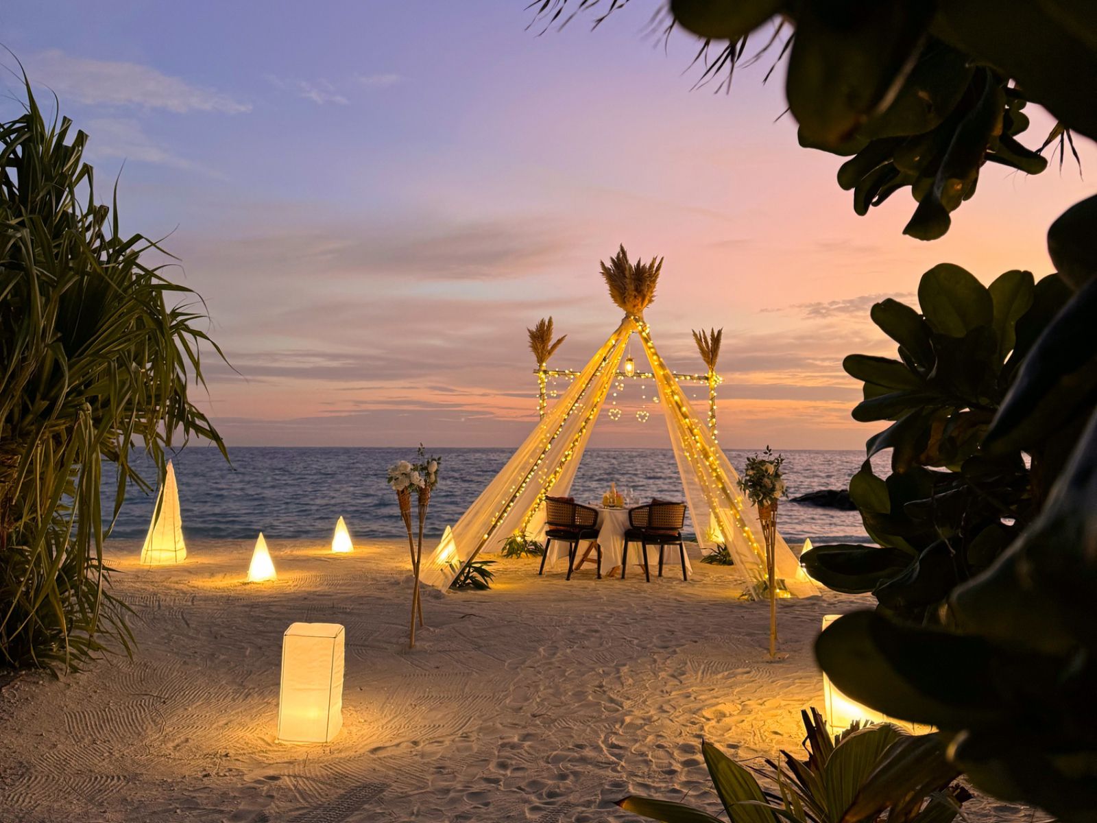 Romantic beachfront proposal under sunset lights