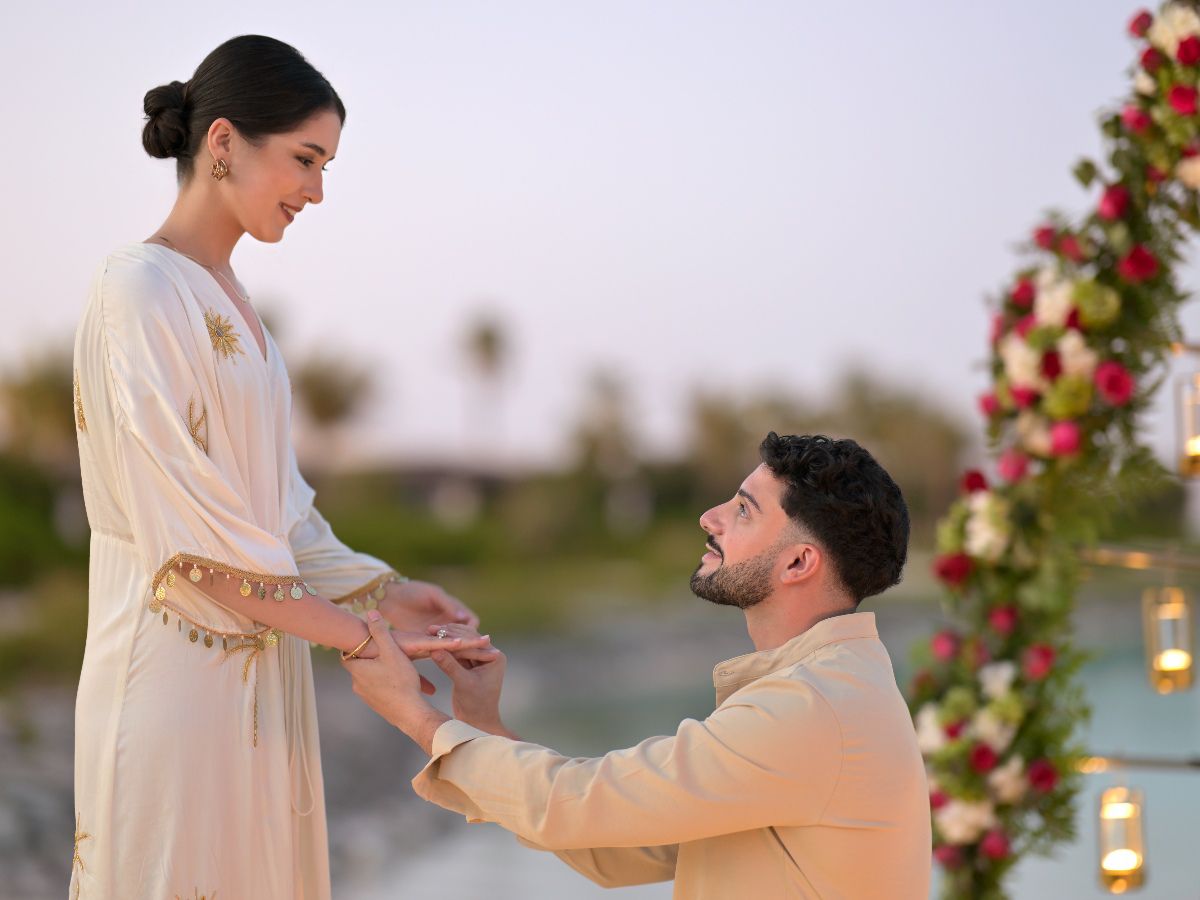 Romantic outdoor proposal beneath elegant floral arch at sunset
