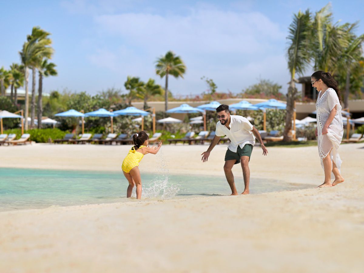 Family enjoying playful beach moments beside turquoise shoreline