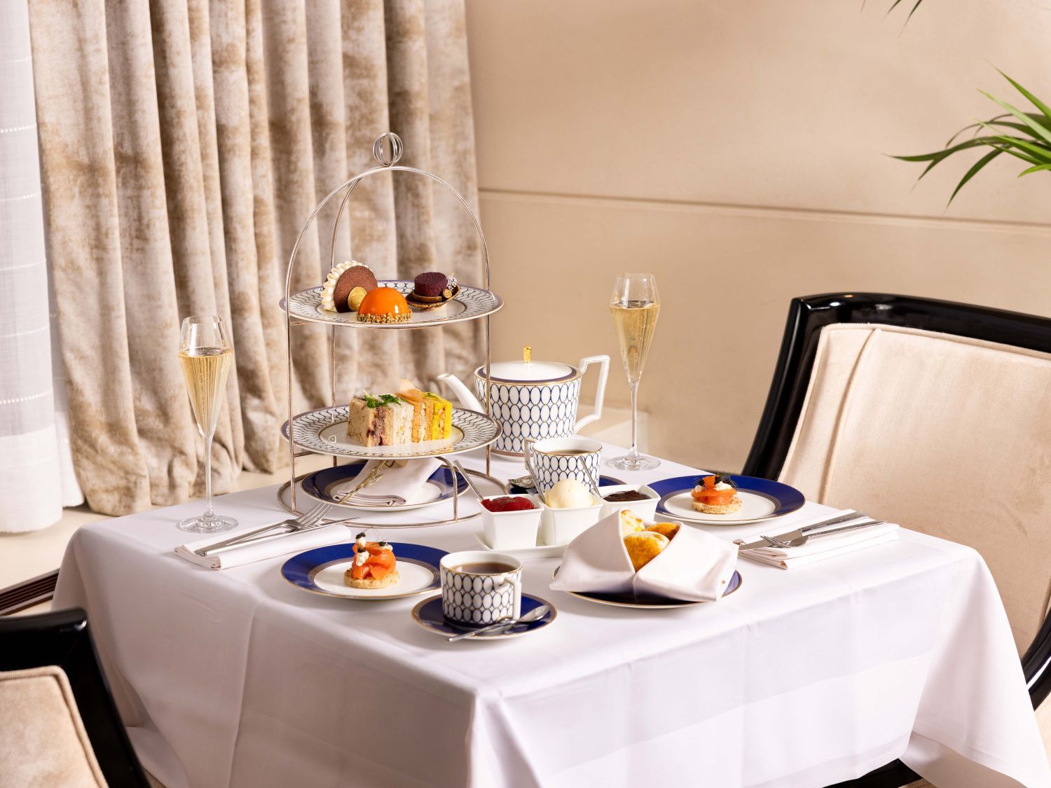 afternoon tea complete set up with scones, sandwiches and mini desserts