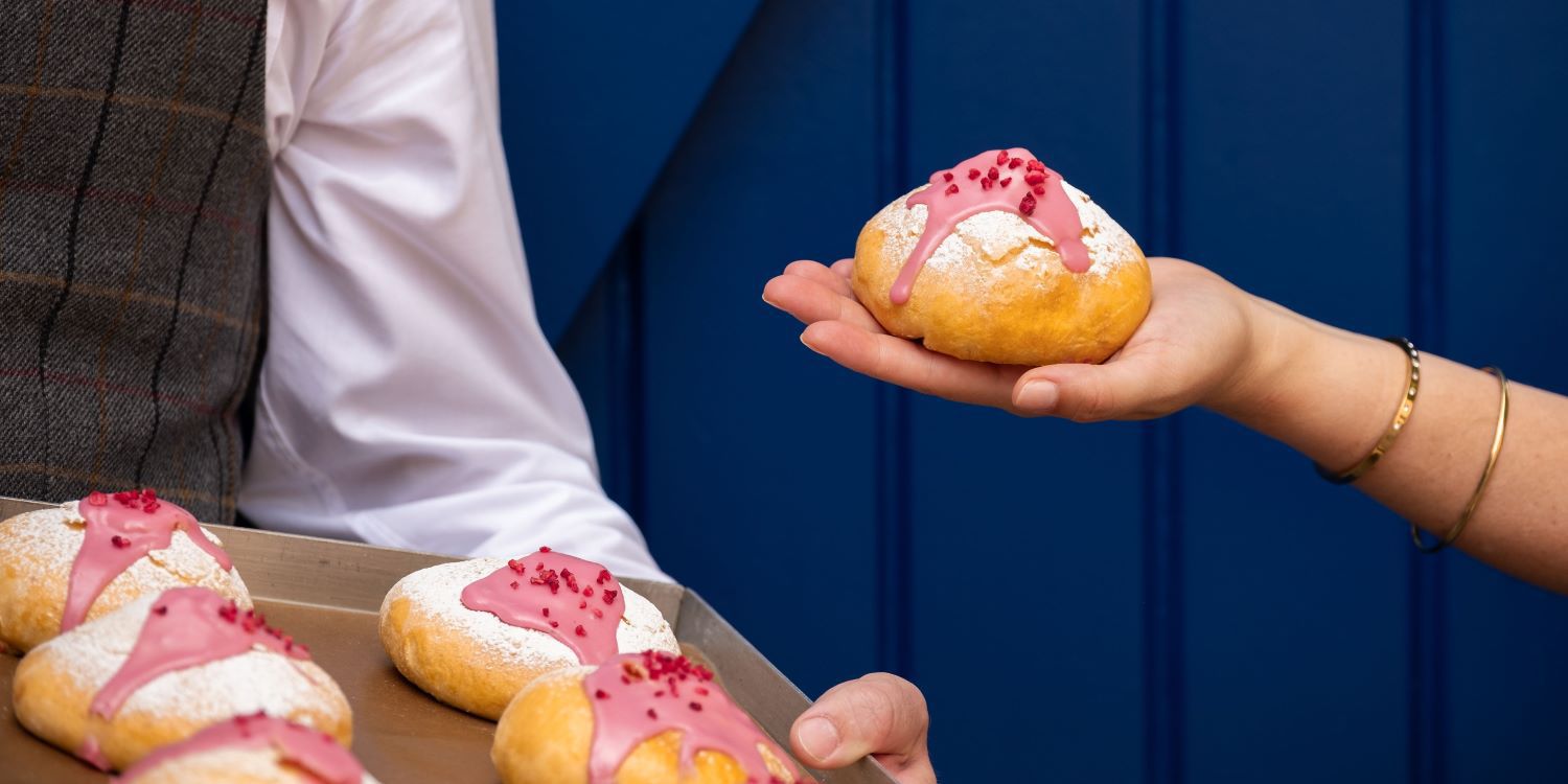 Close up of Kimpton baked bun with pink icing and sugar