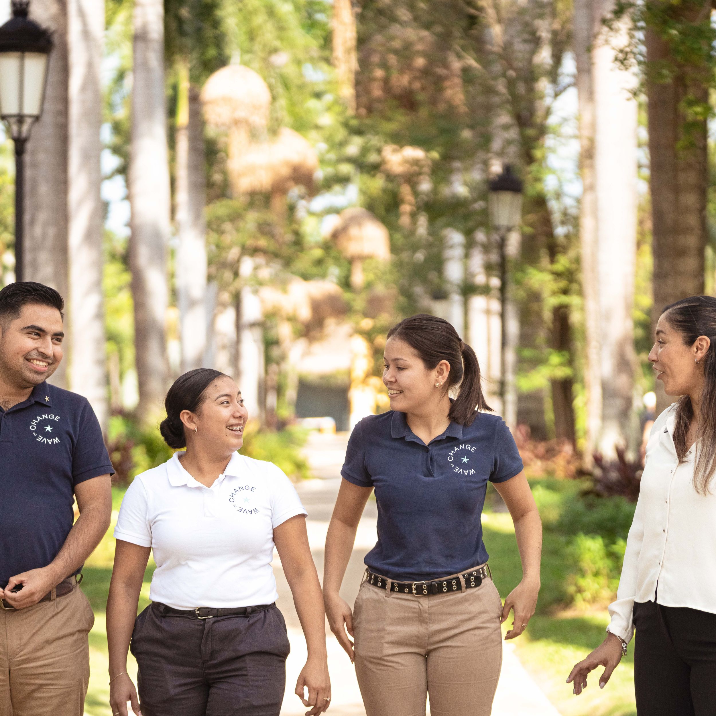 Four workers walking through palm-lined resort path