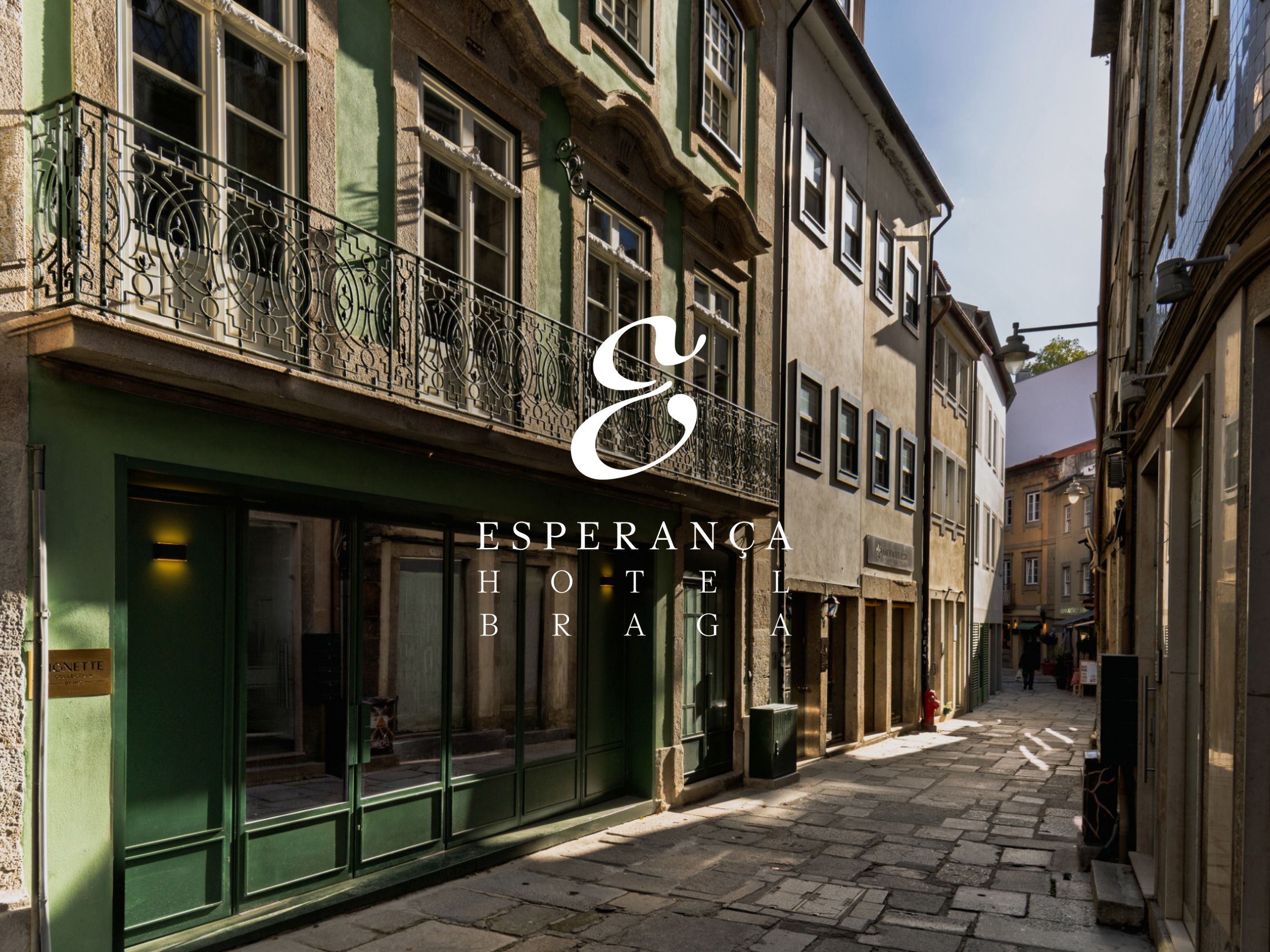 Un logotipo blanco del establecimiento se superpone a una imagen de la entrada de Esperança Hotel Braga