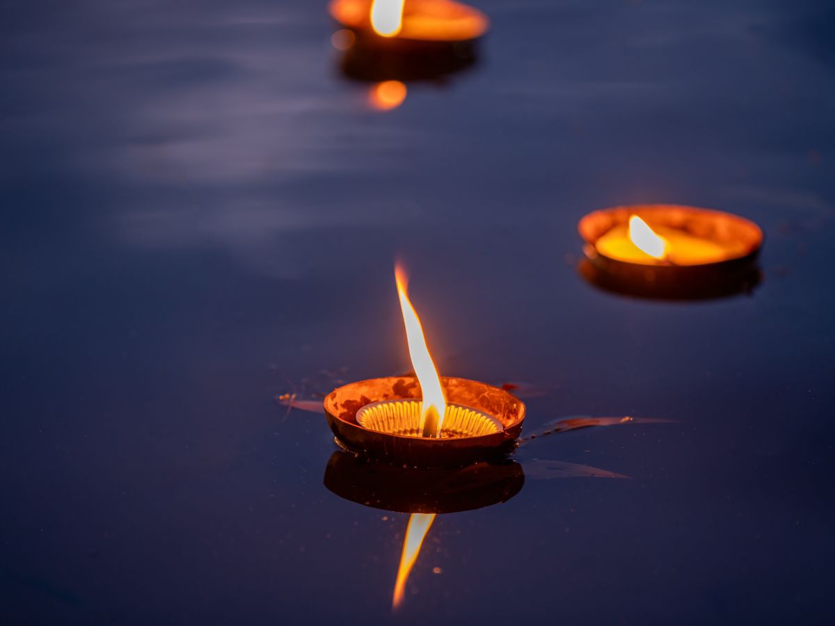 Floating candle lanterns glowing on calm water during a traditional festival celebration.