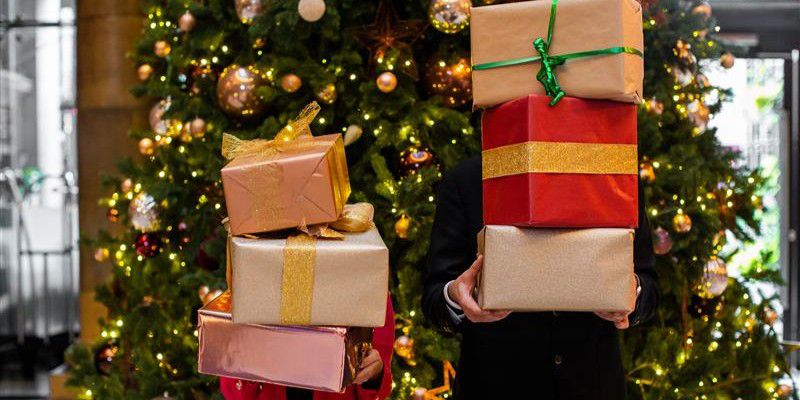 Two people holding plenty Christmas presents
