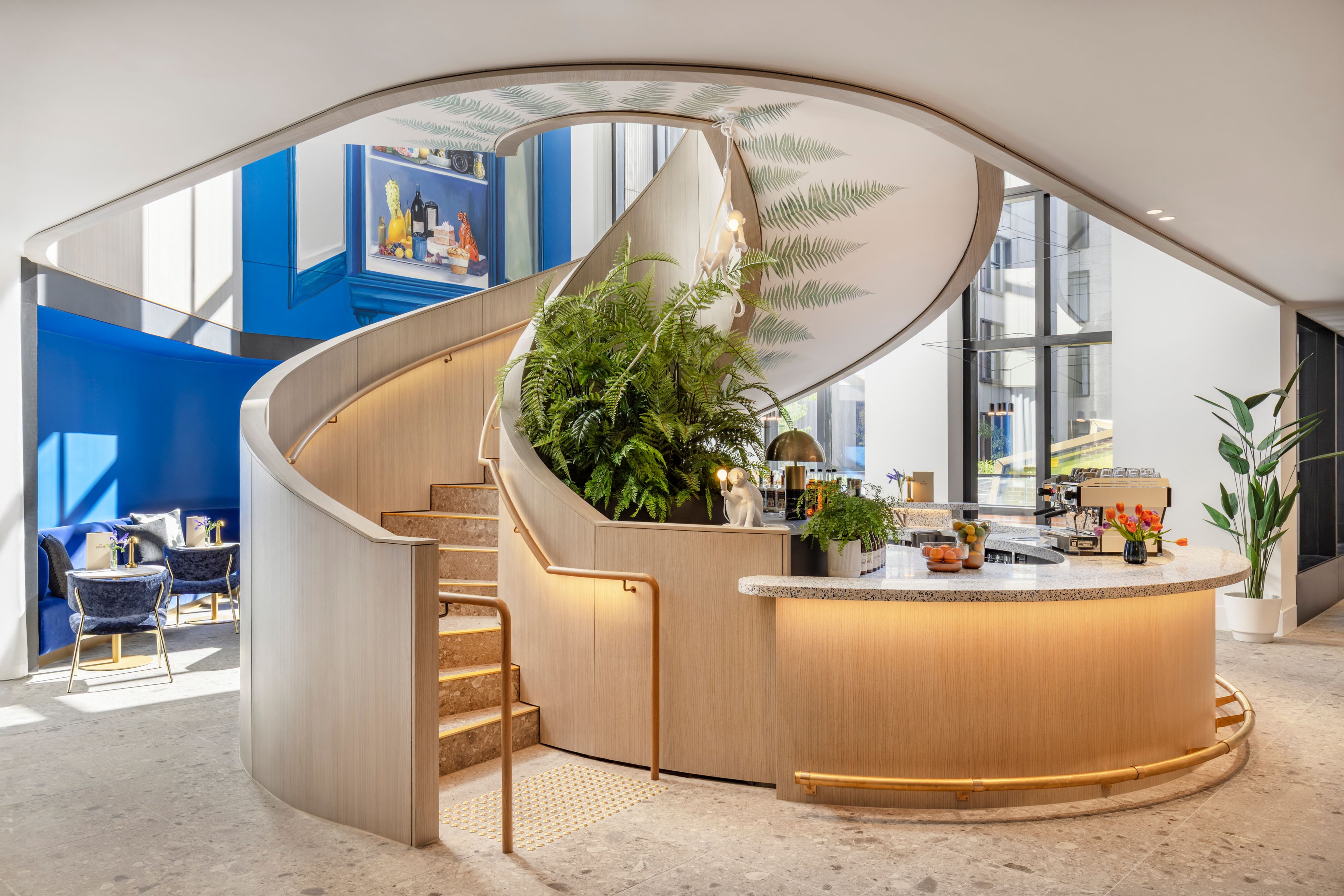 Modern hotel space with curved wood staircase and bar/reception area