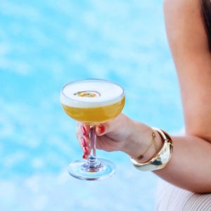 Cocktail held beside a swimming pool by woman